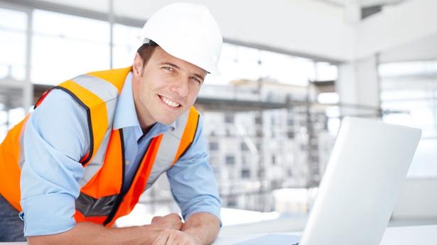 Construction man smiling in front of laptop